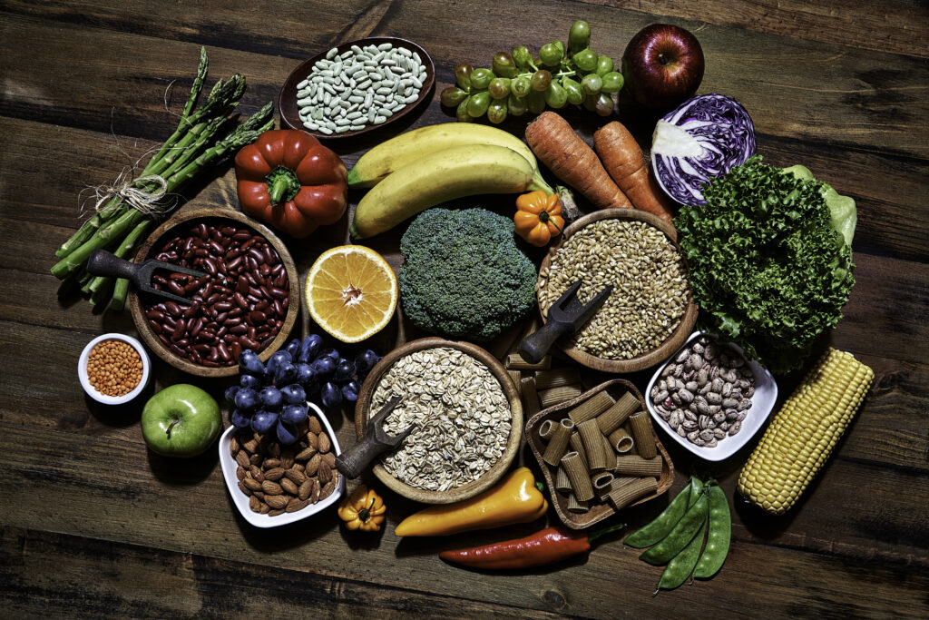 Foods found in plant based diet, including fruit, vegetables, whole grains, beans, legumes, and nuts.